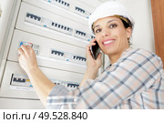 happy female electrician on the phone with fuseboard. Стоковое фото, агентство Ingram Publishing / Фотобанк Лори