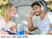 boyfriend outside tent using headphone. Стоковое фото, агентство Ingram Publishing / Фотобанк Лори