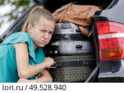 female pushing luggage in car trunk. Стоковое фото, агентство Ingram Publishing / Фотобанк Лори