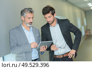 business partners working in hallway with electronic tablet. Стоковое фото, агентство Ingram Publishing / Фотобанк Лори