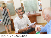 smiling male ophthalmologist and mature patient in modern optics store. Стоковое фото, агентство Ingram Publishing / Фотобанк Лори