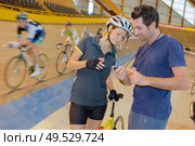 cylist looking at coachs stopwatch as others cycle past. Стоковое фото, агентство Ingram Publishing / Фотобанк Лори
