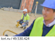builder with theodolite transit equipment at construction site outdoors. Стоковое фото, агентство Ingram Publishing / Фотобанк Лори