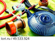Details of tobacco hookah and teapot with tea.Egyptian smoking shisha and teakettle. Arabic shisha with teakettle. Стоковое фото, агентство Ingram Publishing / Фотобанк Лори