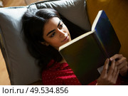 Persian woman at home reading on a couch wearing pyjamas. Persian woman at home reading on a couch. Стоковое фото, агентство Ingram Publishing / Фотобанк Лори