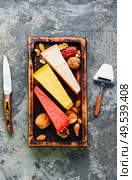 Wooden kitchen board with different kinds of delicious cheese on table. Delicious cheese on the table. Стоковое фото, агентство Ingram Publishing / Фотобанк Лори