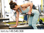 Caucasian strong woman lifting some weights and working on her triceps and biceps in a gym with dumbbells.. Woman working on her triceps and biceps in a gym with dumbbells. Стоковое фото, агентство Ingram Publishing / Фотобанк Лори