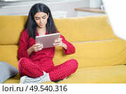 Persian woman at home using digital tablet on a couch. Persian woman at home using digital tablet. Стоковое фото, агентство Ingram Publishing / Фотобанк Лори
