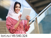 Young Arab woman wearing hijab headscarf using digital tablet in business environment. Young Arab woman wearing hijab using digital tablet outdoors. Стоковое фото, агентство Ingram Publishing / Фотобанк Лори