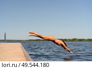 Athletic woman in swimsuit diving headfirst from a pier into the lake. Sunny summer day, dynamic outdoor action. Стоковое фото, фотограф Скоробогатова Е. / Фотобанк Лори