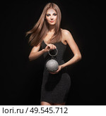 Beautiful young woman in Little black dress. Girl posing on a black background. Blonde girl with long healthy and shiny hair. Care and Beauty. Fashion photo. Glamour lady with a handbag of shiny gems. Стоковое фото, агентство Ingram Publishing / Фотобанк Лори