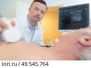 doctor placing ultrasound probe on male patients chest. Стоковое фото, агентство Ingram Publishing / Фотобанк Лори