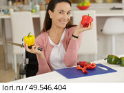 beautiful female in wheelchair holding peper and kitchen knife. Стоковое фото, агентство Ingram Publishing / Фотобанк Лори
