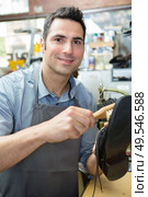 portrait of male cobbler using brush on leather shoe. Стоковое фото, агентство Ingram Publishing / Фотобанк Лори