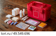 First aid kit displayed on wooden table with various medical supplies organized for easy access. Стоковое AI-изображение, AI-художник Сергей Толмачёв / Фотобанк Лори