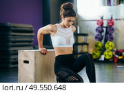 Athletic woman doing triceps push-ups with a wooden box at the gym.. Athletic woman doing triceps push-ups at the gym. Стоковое фото, агентство Ingram Publishing / Фотобанк Лори
