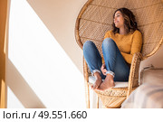 Optimistic woman sitting in a confortable rattan chair at home. Стоковое фото, агентство Ingram Publishing / Фотобанк Лори