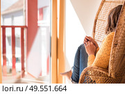 Optimistic woman sitting in a confortable rattan chair at home. Стоковое фото, агентство Ingram Publishing / Фотобанк Лори