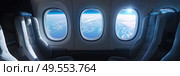 A view from inside an airplane looking out at the wing. The wing with its engines is visible through the window. Стоковое AI-изображение, AI-художник Данила Большаков / Фотобанк Лори