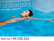 Portrait of beautiful tanned woman in bikini relaxing in swimming pool spa. Hot summer day and bright sunny light.. Beautiful tanned woman in bikini relaxing in swimming pool. Стоковое фото, агентство Ingram Publishing / Фотобанк Лори