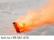 smoke bomb with orange smoke stuck in the white sand. Стоковое фото, агентство Ingram Publishing / Фотобанк Лори