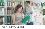 Woman in summer clothes chooses detergent and fabric softener against the background of a customer in a hardware store. Supermarket visitors buy household chemicals. Стоковое видео, видеограф Яков Филимонов / Фотобанк Лори