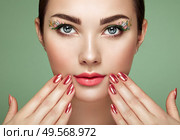 Beauty brunette woman with perfect makeup. Glamour girl. Red lips and nails. Perfect eyebrows. Skin care foundation. Beauty girls face isolated on green background. Fashion photo. Стоковое фото, агентство Ingram Publishing / Фотобанк Лори