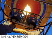 Pilot lighting the burners to heat the air inside the balloon for takeoff. Captive balloons in Aeroestacion Festival in Guadix. Стоковое фото, агентство Ingram Publishing / Фотобанк Лори