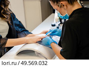 Aesthetician doing the manicure, filing the nails with a file to his client in a beauty center. Business and beauty concepts. Aesthetician doing the manicure, filing the nails with a file to his client in a beauty center. Стоковое фото, агентство Ingram Publishing / Фотобанк Лори
