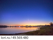 Neowise comet with light tail in night sky over lake Ozero with a beautiful orange sky at sunset or sunrise, Belarus. Стоковое фото, агентство Ingram Publishing / Фотобанк Лори