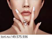 Beauty fashion woman lips with natural Makeup and white nail polish. Gloss brown lipstick. Beauty girl face close up. Sexy lips, manicure, make up. Ring with precious stones, jewelry. Стоковое фото, агентство Ingram Publishing / Фотобанк Лори