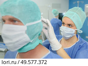 nurse assiting to secure mask on colleague. Стоковое фото, агентство Ingram Publishing / Фотобанк Лори