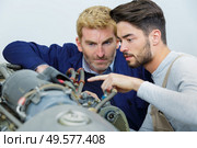 auto mechanic fixing a machine with apprentice. Стоковое фото, агентство Ingram Publishing / Фотобанк Лори