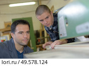 Men aligning wood into machine. Стоковое фото, агентство Ingram Publishing / Фотобанк Лори