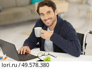 disabled young man using laptop and drinking coffee. Стоковое фото, агентство Ingram Publishing / Фотобанк Лори