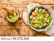 Escargots or snail with garlic butter on rustic wooden background. Bourgogne escargot snails. Стоковое фото, агентство Ingram Publishing / Фотобанк Лори