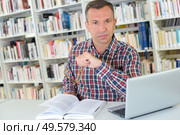 Man in library with book and laptop. Стоковое фото, агентство Ingram Publishing / Фотобанк Лори