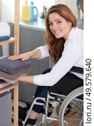 young disabled woman on wheelchair tidying up clean laundry. Стоковое фото, агентство Ingram Publishing / Фотобанк Лори