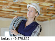 female electrician holding cable indoors. Стоковое фото, агентство Ingram Publishing / Фотобанк Лори