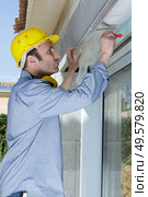 man measuring window prior to installation of roller shutter outdoors. Стоковое фото, агентство Ingram Publishing / Фотобанк Лори
