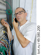 man holds server cable in server rack. Стоковое фото, агентство Ingram Publishing / Фотобанк Лори
