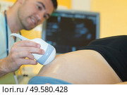 Closeup of ultrasound scanner on pregnant woman's bump. Стоковое фото, агентство Ingram Publishing / Фотобанк Лори
