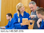 carpenter with female apprentice planing wood in workshop. Стоковое фото, агентство Ingram Publishing / Фотобанк Лори