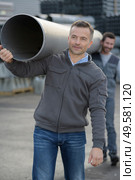 male workers carrying plastic water pipe on their shoulders. Стоковое фото, агентство Ingram Publishing / Фотобанк Лори