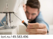man repairing sewing machine with a screwdriver. Стоковое фото, агентство Ingram Publishing / Фотобанк Лори