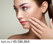 Beauty brunette woman with perfect makeup. Pink lips and nails. Perfect eyebrows. Skin care foundation. Beauty girls face isolated on beige background. Hands with beautiful elegant manicure. Стоковое фото, агентство Ingram Publishing / Фотобанк Лори