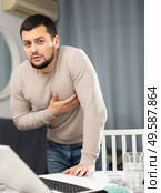 Man experiencing chest pain after working long hours on laptop. Стоковое фото, фотограф Яков Филимонов / Фотобанк Лори