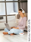 Caucasian blond woman with headphones and laptop on the sofa at home.. Caucasian blond woman with headphones and laptop on the sofa. Стоковое фото, агентство Ingram Publishing / Фотобанк Лори