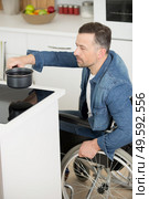 disabled man in wheelchair in the kitchen. Стоковое фото, агентство Ingram Publishing / Фотобанк Лори