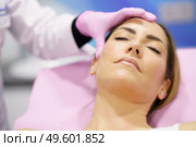 Doctor painting the area of a middle-aged woman’s face where the PDO suture treatment threads will be injected.. Doctor painting the area of a woman’s face where the PDO suture treatment threads will be injected. Стоковое фото, агентство Ingram Publishing / Фотобанк Лори